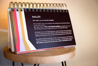 Aufgeschlagener Vorsorge-Kalender mit erklärendem Einführungstext auf einem Hocker.