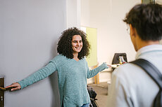 Studienberaterin bittet Studenten zu einem Beratungstermin herein