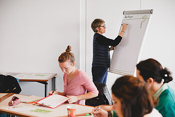 Career-Service-Mitarbeiterin schreibt "Infos" an eine Pinnwand