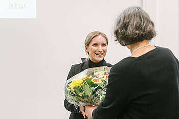 Frau übergibt einer anderen Frau einen Blumenstrauß © HTW Berlin/Alexander Rentsch Frau übergibt einer anderen Frau einen Blumenstrauß