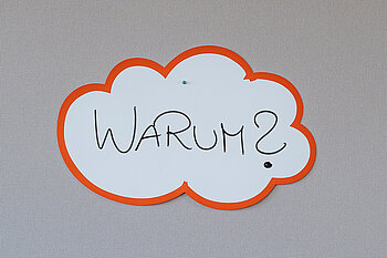Schild mit der Aufschrift "Warum?" an einer Pinnwand