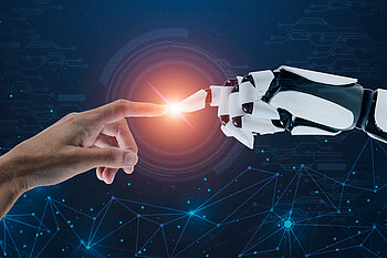 Die Zeigefinger von einem Menschen und einem Roboter berühren sich und es entsteht ein Leuchten an dieser Stelle.