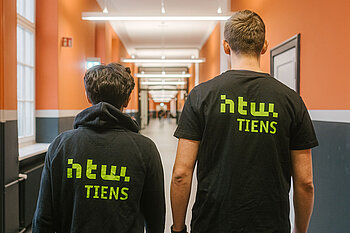 Zwei Studierende mit Pullis, auf denen "HTW-TIENS" steht