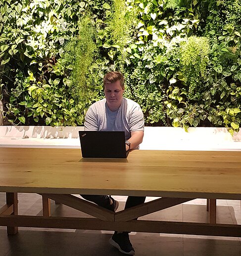Dennis mit Laptop im Grünen