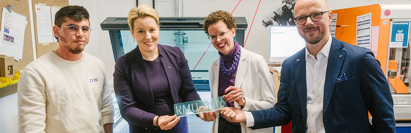 Franziska Giffey, Stefanie Molthagen-Schnöring und Sebastian Stietzel halten ein gerade erstelltes Plexiglas-Schild "KMU-Büro" in den Händen. Links daneben die SHK Tomas Salimbeni.