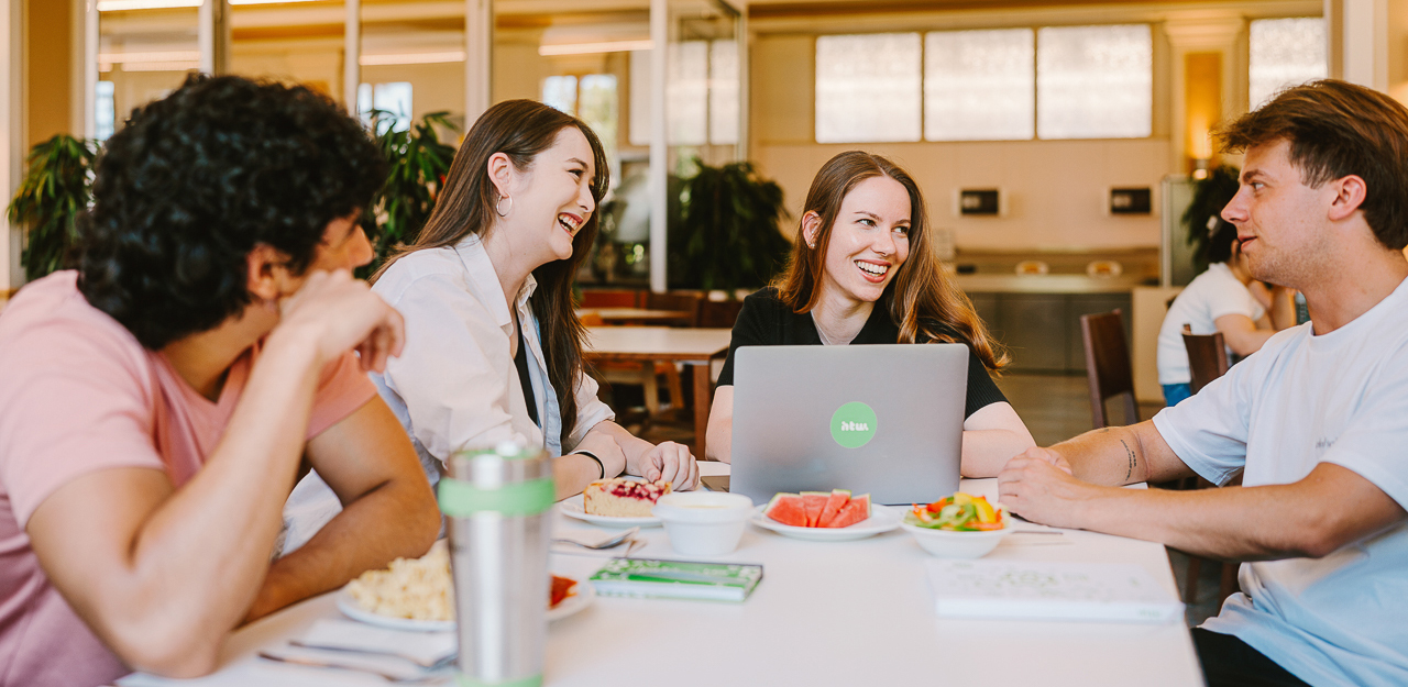 Vier Studierende mit Essen und Laptop in der Mensa auf dem Campus Treskowallee © HTW Berlin/Alexander Rentsch Vier Studierende mit Essen und Laptop in der Mensa auf dem Campus Treskowallee