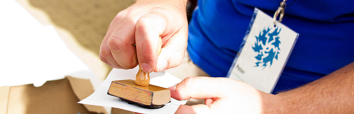 Hand drückt einen Stempel auf Papier