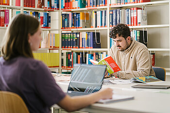 Two students in the library, one student working on a laptop, one student reading a book © HTW Berlin/Alexander Rentsch Two students in the library, one student working on a laptop, one student reading a book