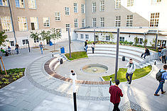 Lebhaftes Studierendentreiben rund um den Springbrunnen am Camus Treskowallee