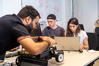 Studierende am Laptop und beim Tüfteln an einem Modellauto © HTW Berlin/Jan-Christoph Hartung