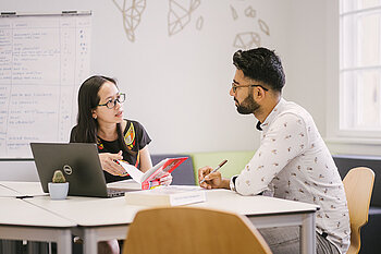 Zwei Studierende mit Laptop an einem Tisch