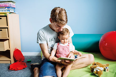 Vater liest seiner kleinen Tochter aus einem Buch vor