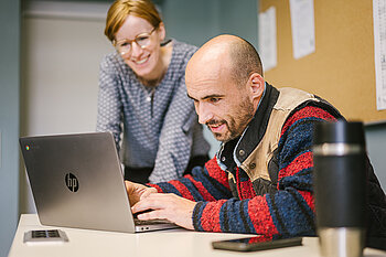 Professorin und Student an einem Laptop