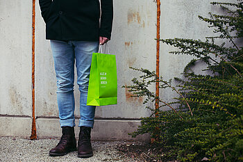 Mensch mit Papiertüte in der Hand