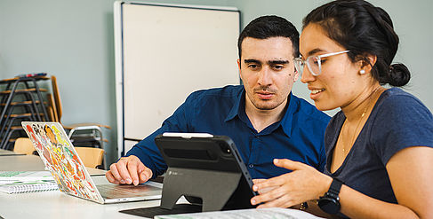 Zwei Studierenden sitzen zusammen an einem Tablet