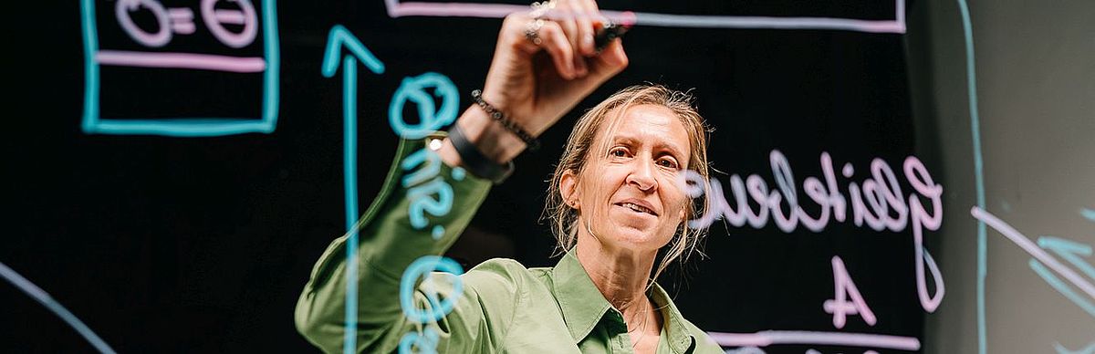 Female professor wrting on a see-through lightboard