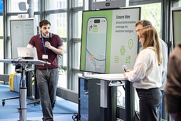 Zwei Studierende mit Mikro vor einem Bildschirm © Toll Collect/Marco Urban