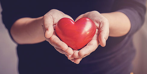 Hände mit einem roten Stein in Herzform © istockphoto.com