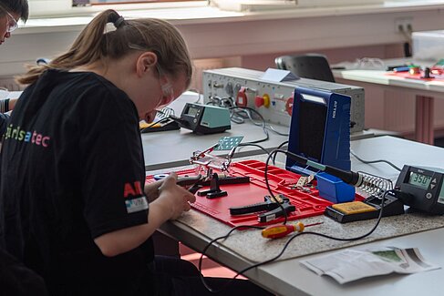 Junge Frau sitzt an einem Tisch mit Werkzeug und Elektroden ©   O ja! Orientierungsjahr