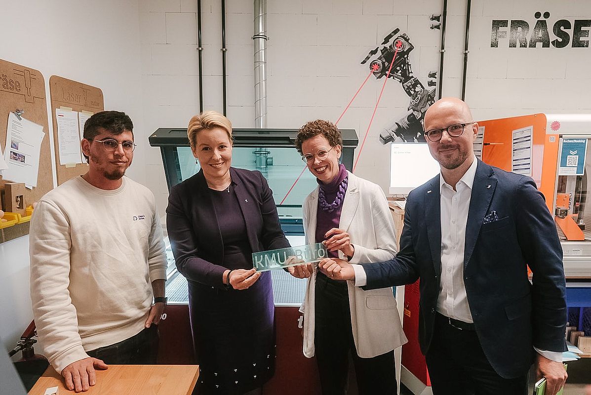 Tomas Salimbeni, Fanziska Giffey, Prof. Dr. Stefanie Molthagen-Schnöring und Sebastian Stietzel im IDiA Maker Space mit dem gerade ausgefrästen Schild "KMU Büro" © HTW Berlin/Alexander Rentsch