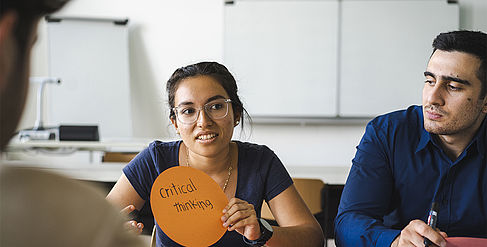 Studentin mit der Notiz "Critical Thinking" in der Hand