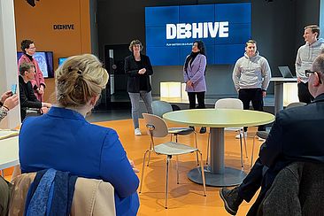 Franziska Giffey und Oliver Igel sehen sich eine Präsentation an, im Hintergrund eine Leinwand mit dem Schriftzug DE:HIVE © HTW Berlin/Maria Schmidt