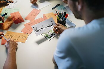 A student holds a sign saying "What is important?"
