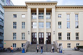 Studierende gehen die Treppe vor einem historischen Hochschulgebäude am Campus Treskowallee hinunter.