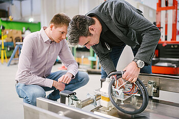 Zwei Männer über einer Batterie