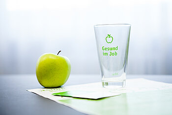 Apfel und Glas mit der Aufschrift "Gesund im Job"