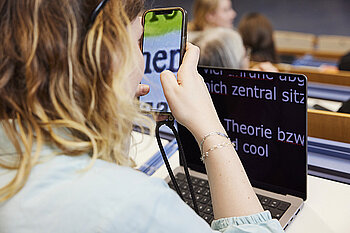 Frau bedient Smartphone mit stark vergrößerter Schrift, auf dem Tisch ein Laptop mit ebenfalls stark vergrößerter Schrift © Anna Spindelndreier | helloyou.studio | Gesellschaftsbilder.de Frau bedient Smartphone mit stark vergrößerter Schrift, auf dem Tisch ein Laptop mit ebenfalls stark vergrößerter Schrift