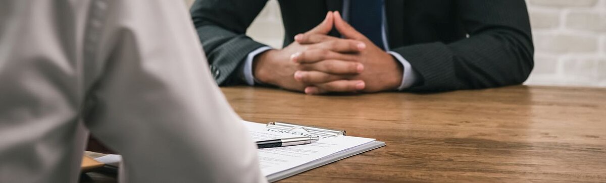 Zwei Personen am Verhandlungstisch mit Vertragsunterlagen