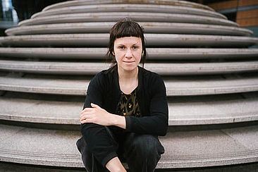 Prof. Dr. Helena Mihaljevic sitzt auf einer leeren Stein-Treppe.