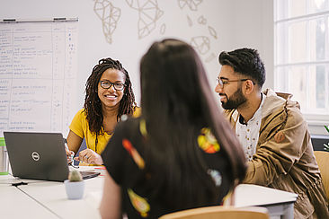 Drei Studierende sitzen an einem Tisch und diskutieren, im Hintergrund ist eine stilisierten Weltkarte zu sehen © HTW Berlin/Alexander Rentsch Drei Studierende sitzen an einem Tisch und diskutieren, im Hintergrund ist eine stilisierten Weltkarte zu sehen © HTW Berlin/Alexander Rentsch