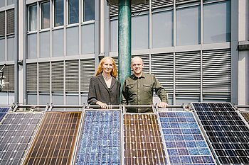 Frau und Mann hinter einem Solarmodul
