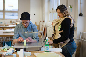 Studentin mit ihrem Kind in einer Babytrage in einer Lehrveranstaltung