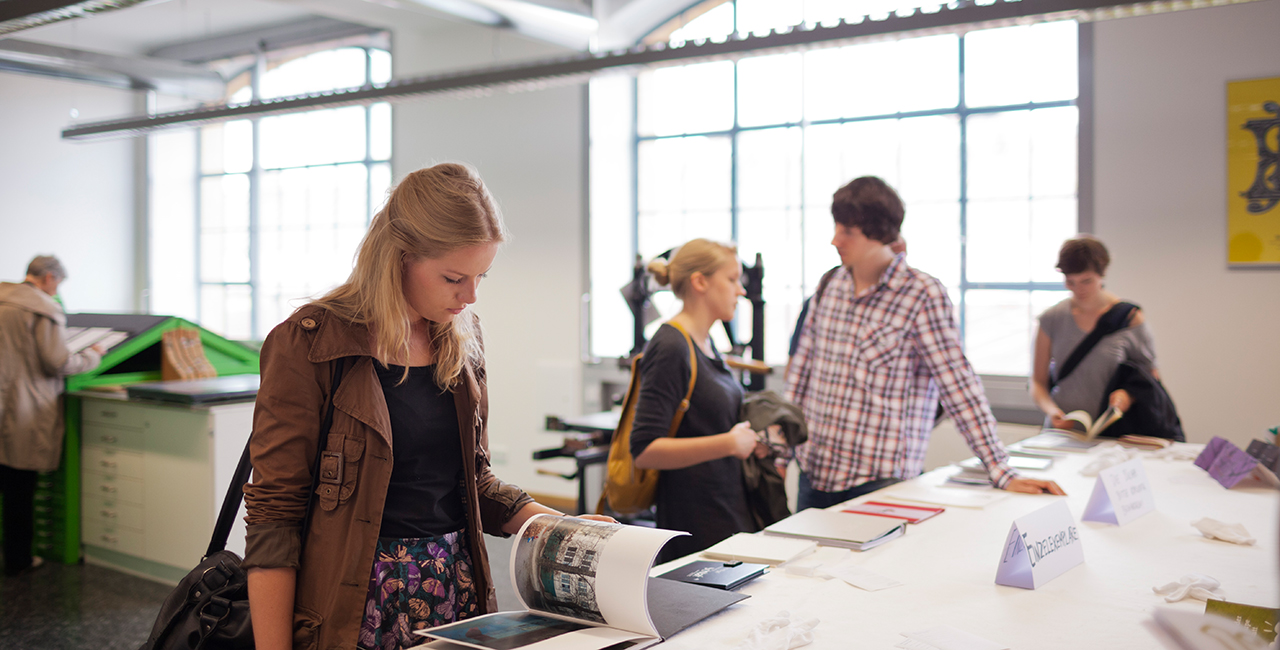 Besucherin blättert bei der Werkschau in einem Ausstellungsobjekt © HTW Berlin/Alexander Rentsch Besucherin blättert bei der Werkschau in einem Ausstellungsobjekt