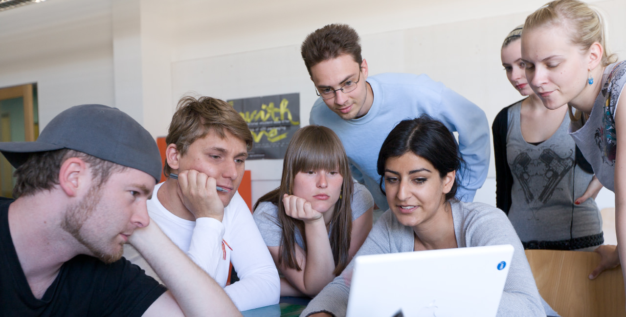 Students grouped around a laptop