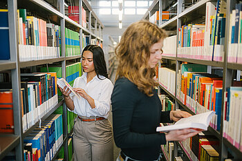 Zwei Studentinnen mit Jura-Büchern in der Bibliothek